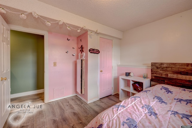 bedroom featuring wood finished floors, a textured ceiling, and baseboards