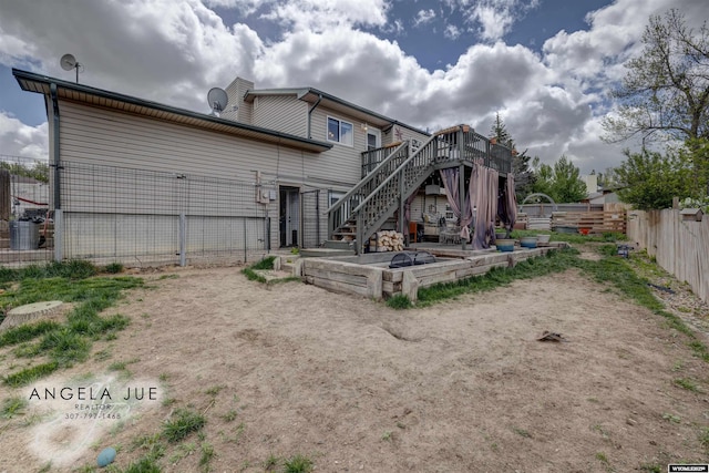 back of property with stairway, a deck, and fence