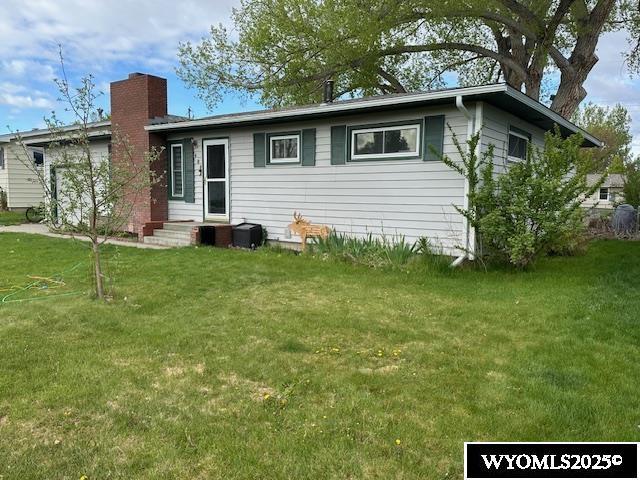 408 S 18th, Worland, WY 82401 - back of house featuring a chimney and a lawn