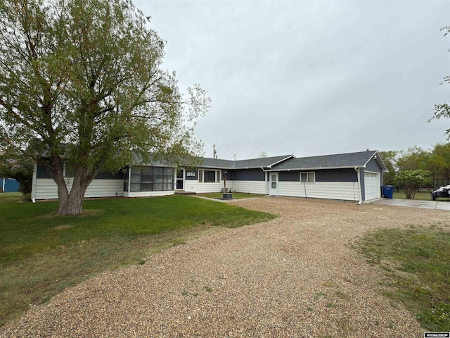 ranch-style home with driveway, an attached garage, a front lawn, and a sunroom