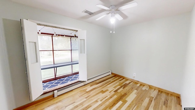 empty room with baseboard heating, wood finished floors, and a ceiling fan