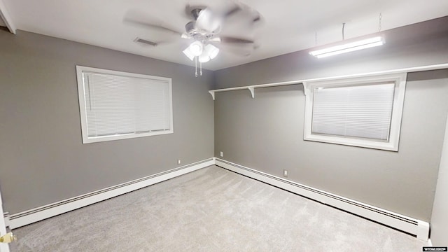 carpeted spare room featuring ceiling fan and a baseboard heating unit