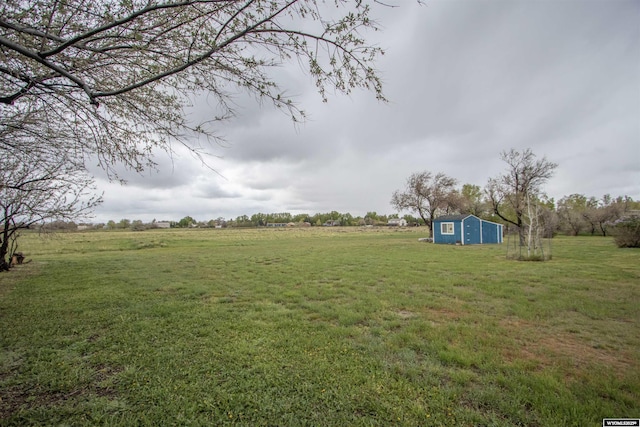view of grassy yard with an outbuilding and a rural view