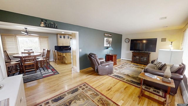 living area with ceiling fan, light wood-type flooring, and baseboards