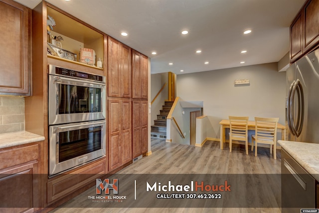 kitchen with appliances with stainless steel finishes, recessed lighting, light wood finished floors, brown cabinets, and tasteful backsplash