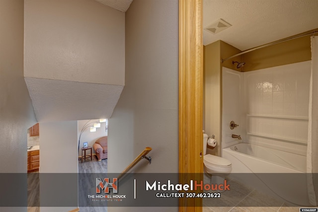 bathroom with a textured ceiling, toilet, tile patterned floors, and shower / tub combination