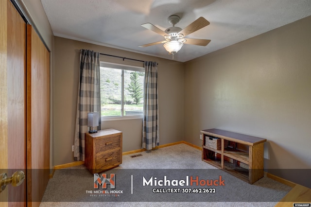 carpeted office space with ceiling fan and baseboards