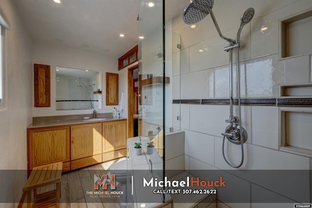 bathroom with tiled shower, recessed lighting, and vanity