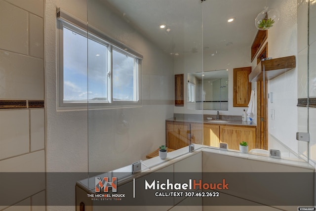 bathroom featuring vanity, recessed lighting, and a textured wall