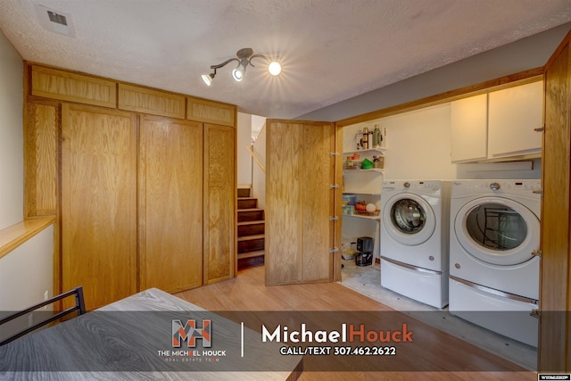 laundry room with light wood-style floors, washing machine and clothes dryer, and cabinet space