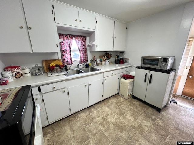 1208 10th St, Wheatland, WY 82201 - kitchen with light countertops, white cabinetry, stone finish floors, and a sink