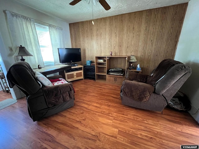 1208 10th St, Wheatland, WY 82201 - living room featuring wood finished floors, a textured ceiling, wood walls, and ceiling fan