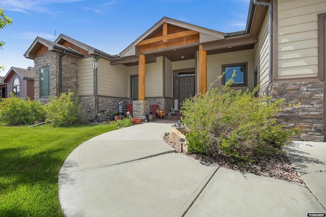 property entrance featuring stone siding and a lawn