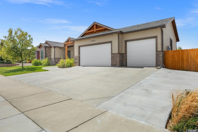 view of front facade with stone siding, driveway, a garage, and fence