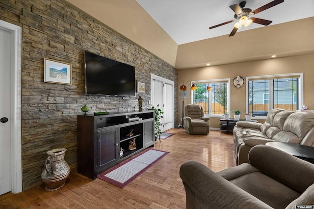 living area with a ceiling fan, light wood finished floors, and high vaulted ceiling