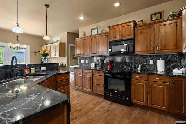 kitchen with black appliances, a sink, brown cabinets, decorative backsplash, and wood finished floors