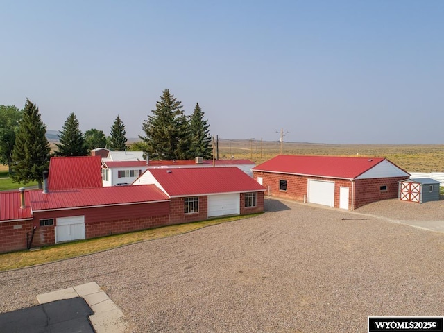 19A Kolman Ranch Rd, Rock Springs, WY 82901 - view of front of property with a detached garage, metal roof, an outbuilding, brick siding, and dirt driveway