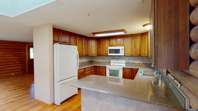 7 Raschell Ct, Lander, WY 82520 - kitchen featuring white appliances, a sink, light wood-style floors, a peninsula, and tasteful backsplash
