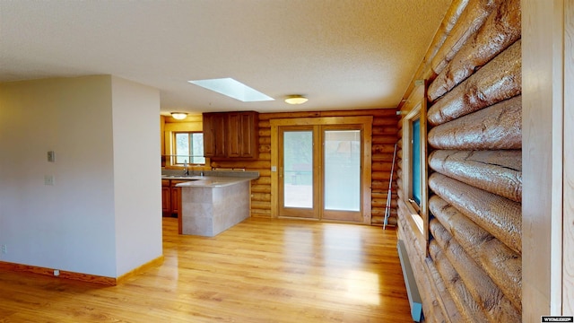 7 Raschell Ct, Lander, WY 82520 - kitchen featuring log walls, a skylight, light wood-type flooring, a sink, and a textured ceiling