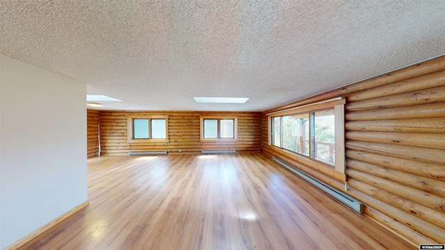 7 Raschell Ct, Lander, WY 82520 - spare room featuring a skylight, rustic walls, baseboard heating, a textured ceiling, and light wood finished floors