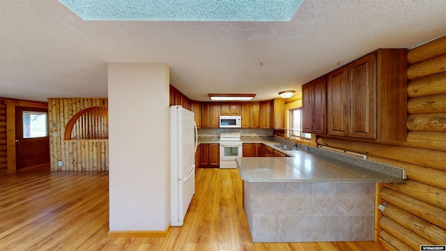 7 Raschell Ct, Lander, WY 82520 - kitchen with white appliances, a sink, rustic walls, a textured ceiling, and a peninsula