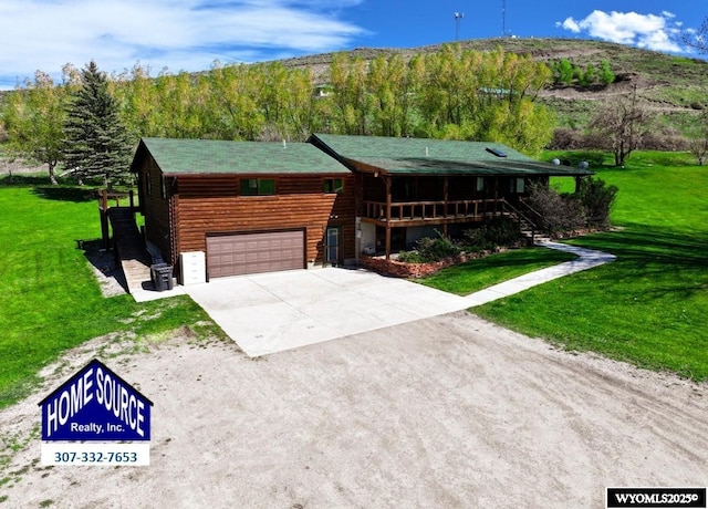 7 Raschell Ct, Lander, WY 82520 - cabin featuring concrete driveway, an attached garage, a front lawn, and covered porch