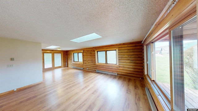7 Raschell Ct, Lander, WY 82520 - spare room with log walls, a skylight, baseboard heating, light wood-style floors, and a textured ceiling