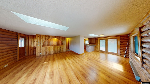 7 Raschell Ct, Lander, WY 82520 - unfurnished living room featuring a skylight, light wood-type flooring, a textured ceiling, and rustic walls