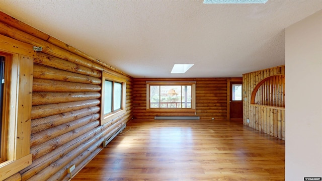 7 Raschell Ct, Lander, WY 82520 - unfurnished living room featuring a baseboard heating unit, light wood finished floors, a skylight, a textured ceiling, and rustic walls