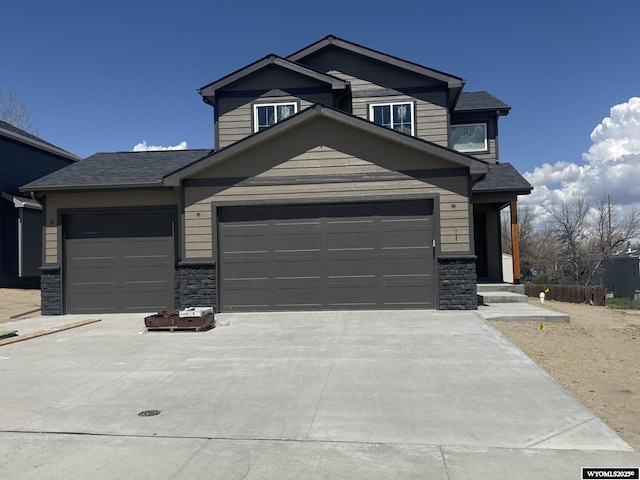 view of front of house featuring concrete driveway, stone siding, a garage, and a shingled roof