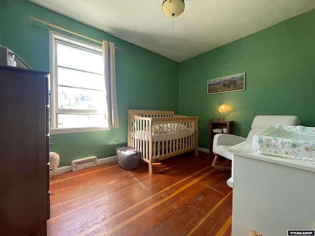 309 Cedar Ave, Kemmerer, WY 83101 - bedroom with hardwood / wood-style floors, baseboards, and a nursery area
