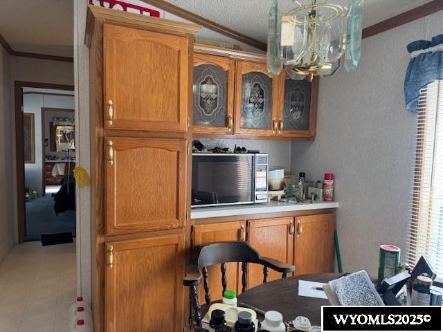 170 Eardley Ave, Fort Bridger, WY 82933 - bar with crown molding, stainless steel microwave, a chandelier, vaulted ceiling, and a textured ceiling