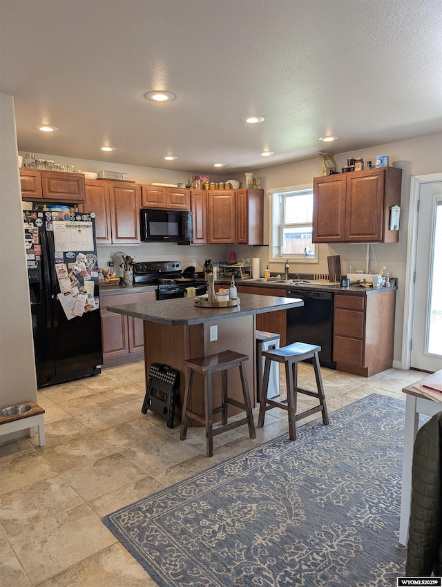 1206 E Park Ave, Riverton, WY 82501 - kitchen with black appliances, dark countertops, a kitchen bar, a kitchen island, and brown cabinetry