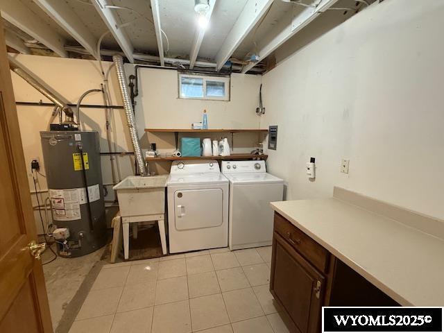 221 Fir St, Buffalo, WY 82834 - washroom featuring water heater, washing machine and clothes dryer, light tile patterned floors, and cabinet space