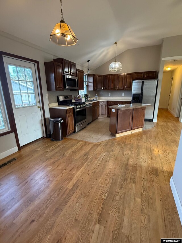 221 Fir St, Buffalo, WY 82834 - kitchen featuring appliances with stainless steel finishes, light wood-style floors, lofted ceiling, decorative light fixtures, and dark brown cabinets