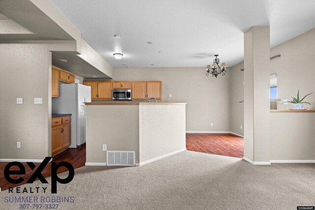 2521 Sagewood Ave, Casper, WY 82601 - kitchen featuring white refrigerator with ice dispenser, stainless steel microwave, dark colored carpet, a chandelier, and baseboards