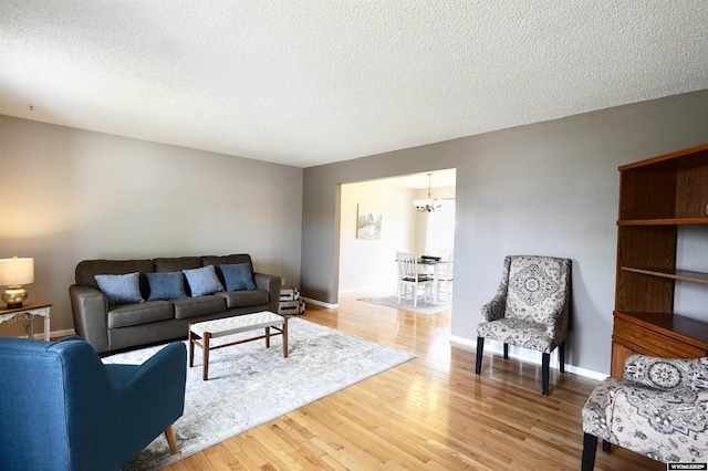 4451 S David St, Casper, WY 82601 - living area featuring a chandelier, light wood-style floors, a textured ceiling, and baseboards