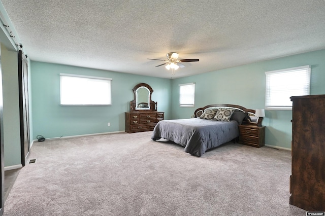 4451 S David St, Casper, WY 82601 - bedroom featuring carpet floors, a textured ceiling, a ceiling fan, baseboards, and a barn door