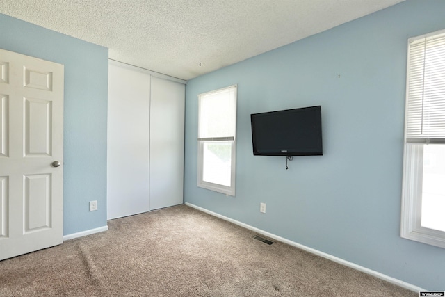 4451 S David St, Casper, WY 82601 - unfurnished bedroom with multiple windows, carpet floors, a closet, a textured ceiling, and baseboards