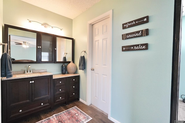 4451 S David St, Casper, WY 82601 - bathroom featuring wood finished floors, vanity, a textured ceiling, and baseboards