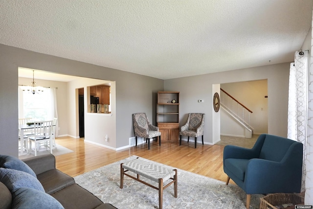 4451 S David St, Casper, WY 82601 - living room with a chandelier, light wood-style flooring, a textured ceiling, stairway, and baseboards