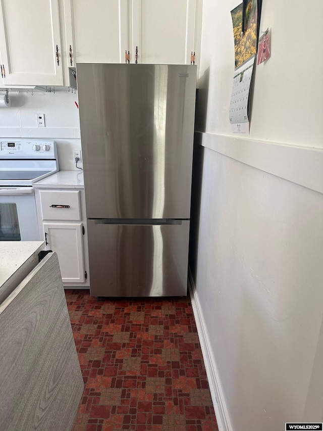 101 9th, Sinclair, WY 82334 - kitchen featuring freestanding refrigerator, white electric range, white cabinets, and brick patterned flooring