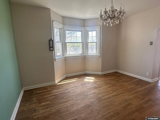 101 9th, Sinclair, WY 82334 - empty room featuring wood finished floors, a chandelier, baseboards, and arched walkways