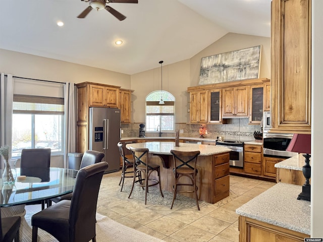 617 Lucille Cir, Evanston, WY 82930 - kitchen with stainless steel appliances, a breakfast bar area, a kitchen island, brown cabinetry, and decorative backsplash