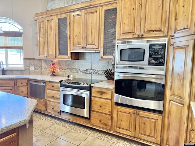 617 Lucille Cir, Evanston, WY 82930 - kitchen featuring appliances with stainless steel finishes, light tile patterned floors, tasteful backsplash, and a sink