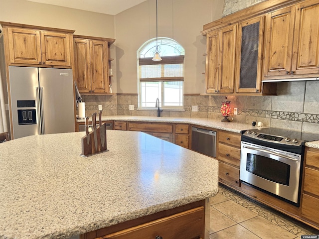 617 Lucille Cir, Evanston, WY 82930 - kitchen with stainless steel appliances, brown cabinetry, tasteful backsplash, a sink, and light tile patterned flooring