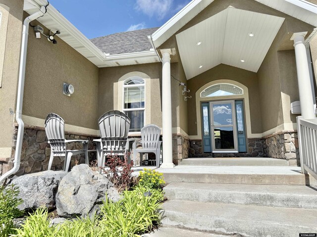 617 Lucille Cir, Evanston, WY 82930 - property entrance with stone siding, stucco siding, a shingled roof, and a porch