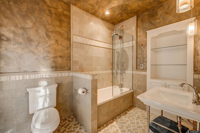 1108 S Wolcott St, Casper, WY 82601 - full bathroom with tile walls, tiled shower / bath, toilet, a sink, and tile patterned flooring