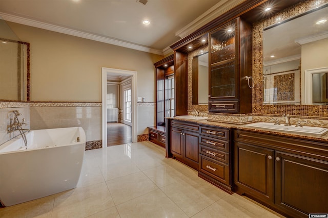 1108 S Wolcott St, Casper, WY 82601 - bathroom featuring a freestanding bath, crown molding, double vanity, tile patterned flooring, and tile walls