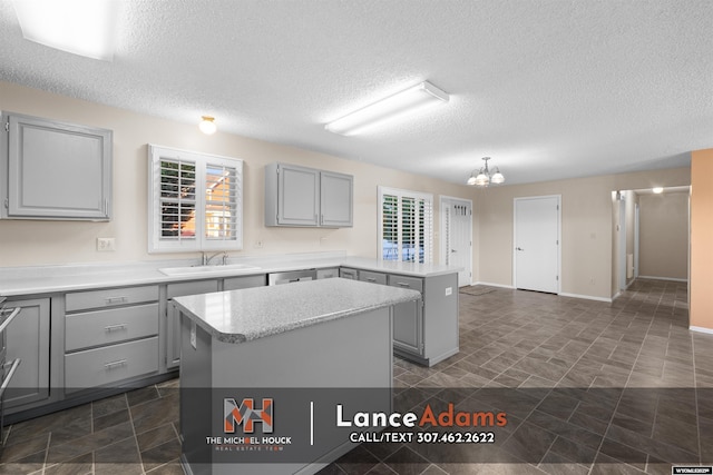 396 Williams Way, Glenrock, WY 82637 - kitchen with a sink, gray cabinets, a peninsula, a kitchen island, and a textured ceiling